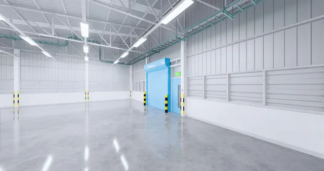 An empty warehouse with a blue door and a concrete floor.