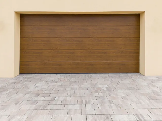 A wooden garage door with a brick driveway in front of it