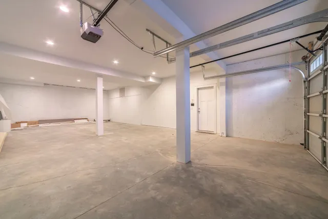 An empty garage with a garage door open and a ceiling fan.