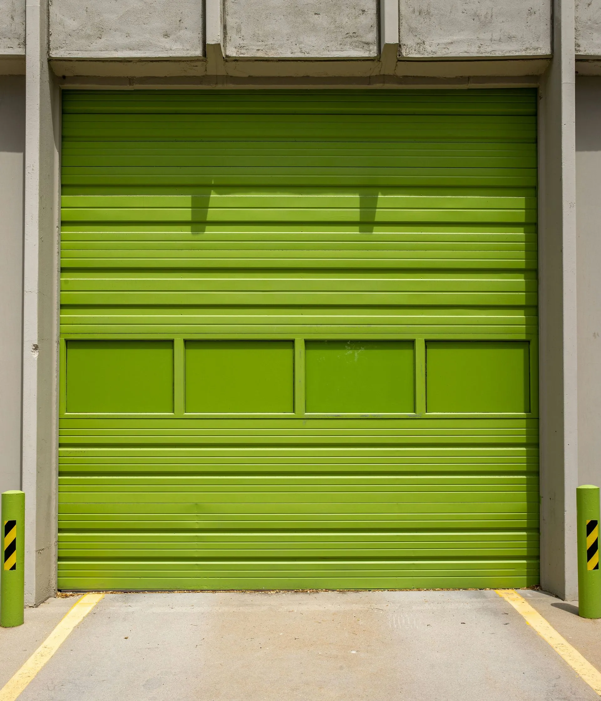 A green garage door is open in a parking lot.