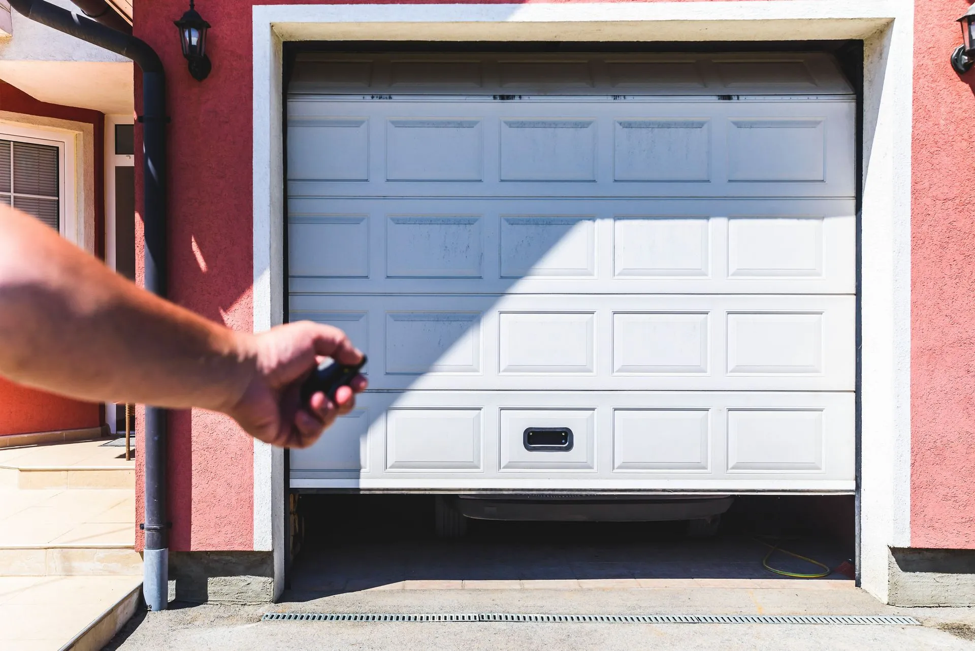 A person is opening a garage door with a remote control.